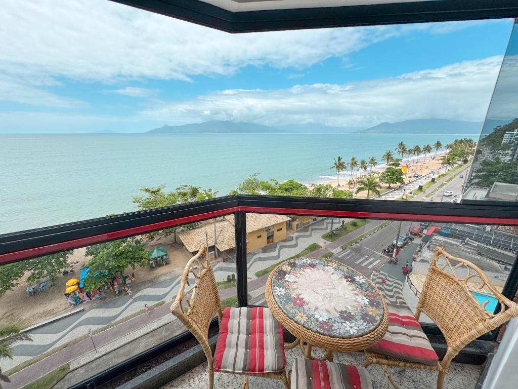 Un balcón con sillas y vista al mar. en Apt Pé na Areia - Praia Martim de Sá - Espaço Gourmet na Varanda e Piscina, en Caraguatatuba