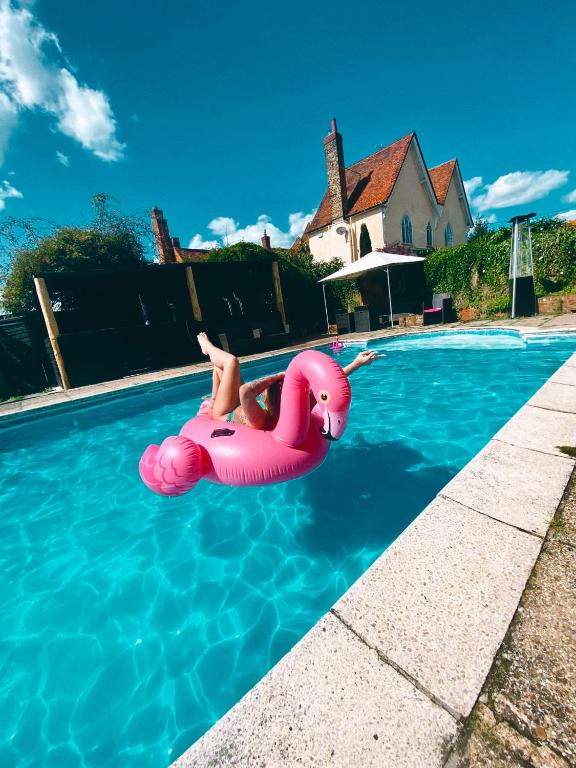 a woman is floating on an inflatable at Grade II Listed Farmhouse, Pool, Hot Tub, Games Room, Celebration Hall, Car Park, 10ppl, 45 min from Central London in Stapleford Tawney