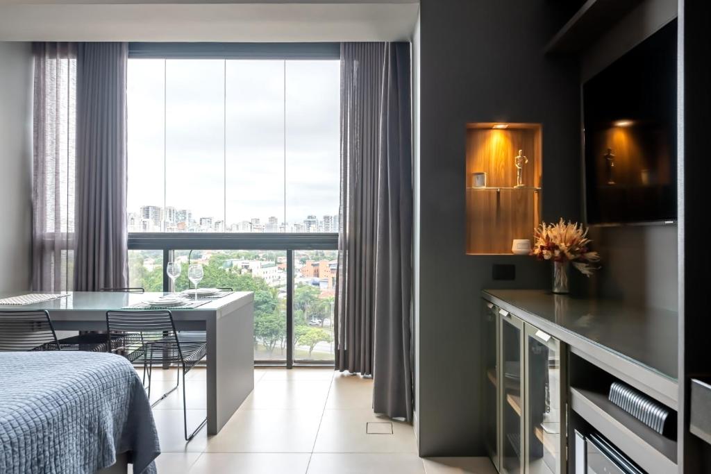 a bedroom with a bed and a table and a window at Studio Style - Vila Olímpia in Sao Paulo