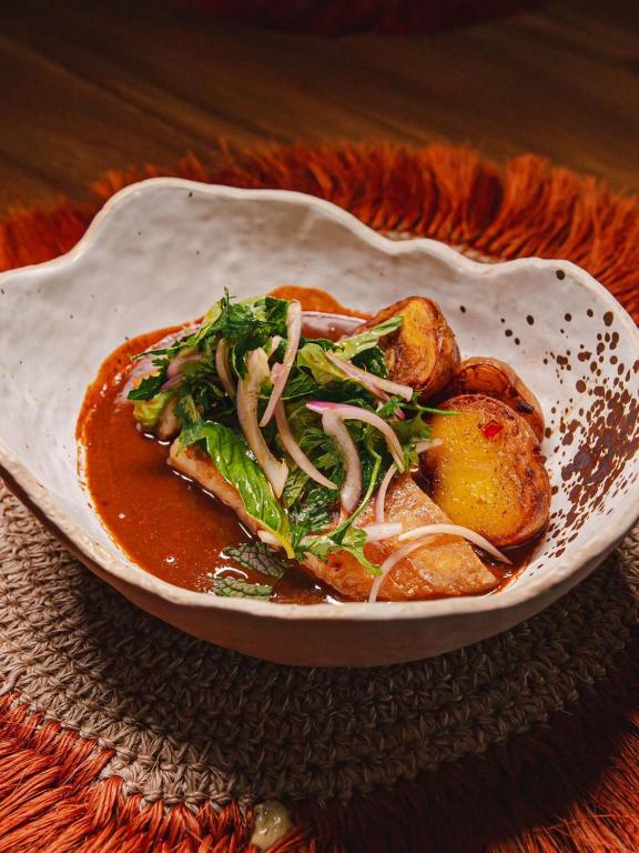 a white bowl of food with vegetables and sauce at Casa Coraje in Palomino