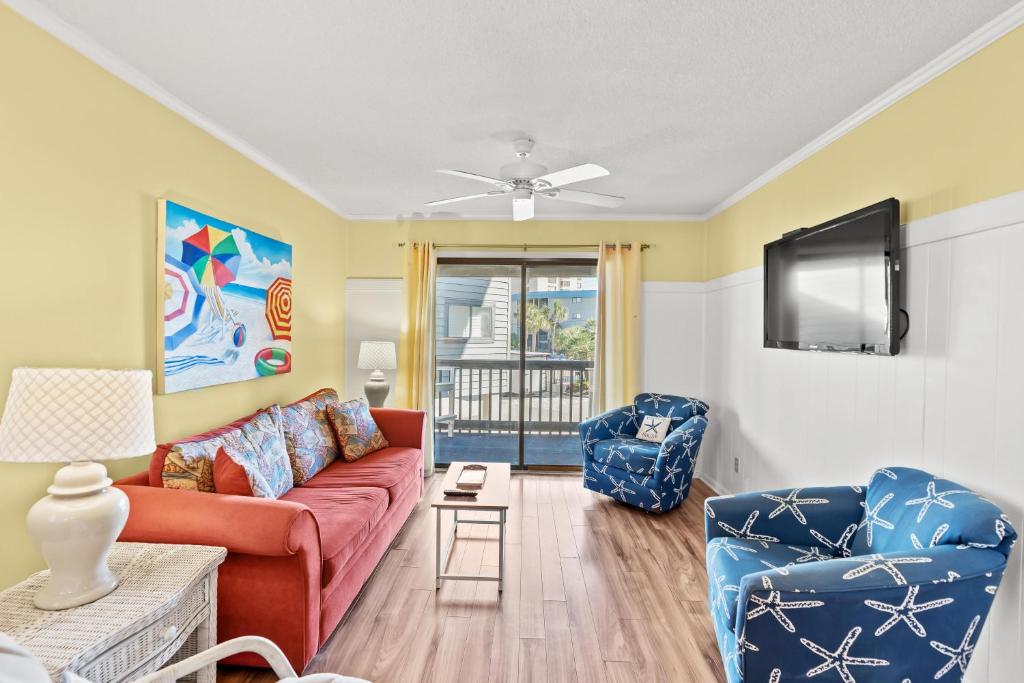 a living room with a red couch and two chairs at Sea Cabin 147 - 2nd Row - Cherry Grove Section in Myrtle Beach