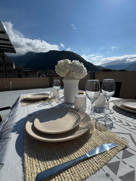 a table with plates and wine glasses on a table at Luxury Penthouse with Jacuzzy 6 bedroom in Baños