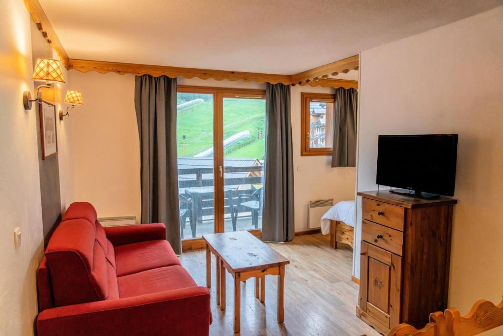 un salon avec un canapé rouge et une télévision dans l'établissement Résidence Les Hauts De Preclaux - Appartement duplex avec balcon face aux pistes MAE-7271, aux Orres