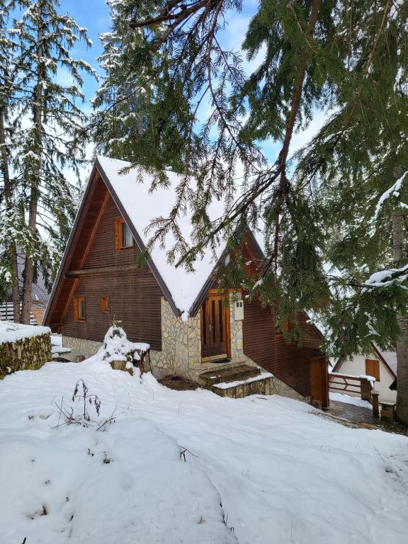 a cabin with snow on the roof in the woods at Cozy Cottage Vlašić in Vlasic