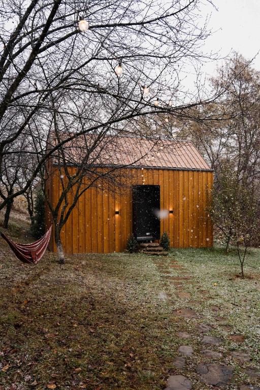 a wooden building with a door in a yard at Căsuța din livadă in Măneciu