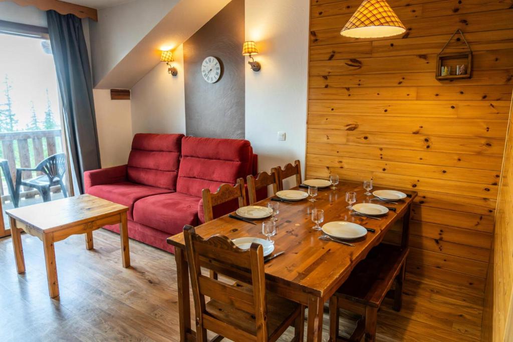 - une salle à manger avec une table et un canapé rouge dans l'établissement Résidence Les Hauts De Preclaux - Confortable appartement pour 8 personnes MAE-9191, aux Orres