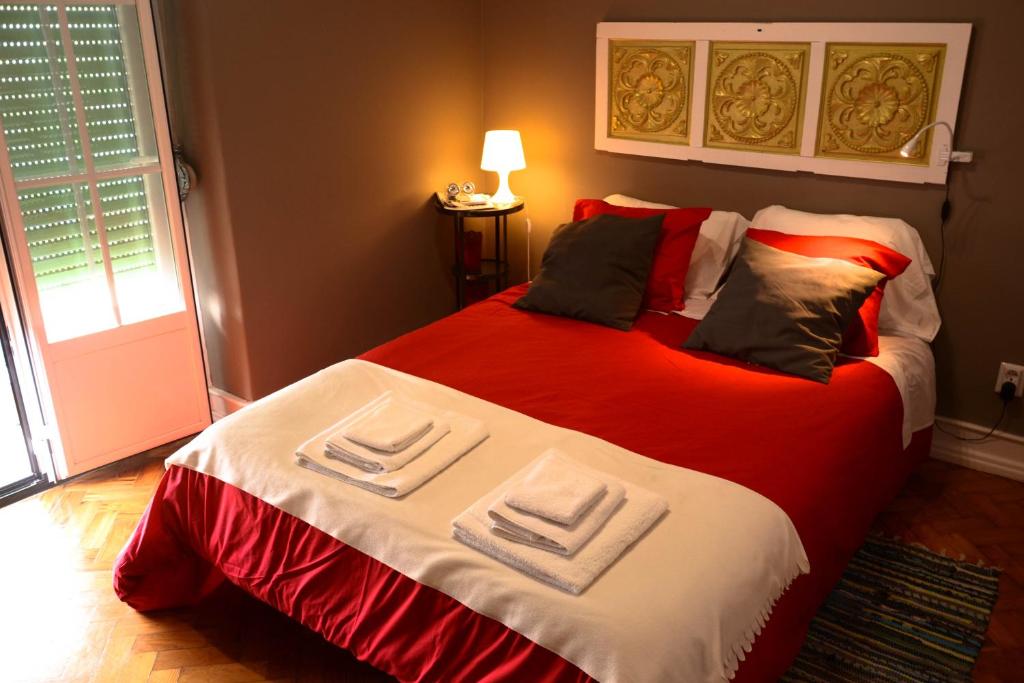 a bedroom with a large bed with red and white sheets at Alvalade II Airport Guest House in Lisbon