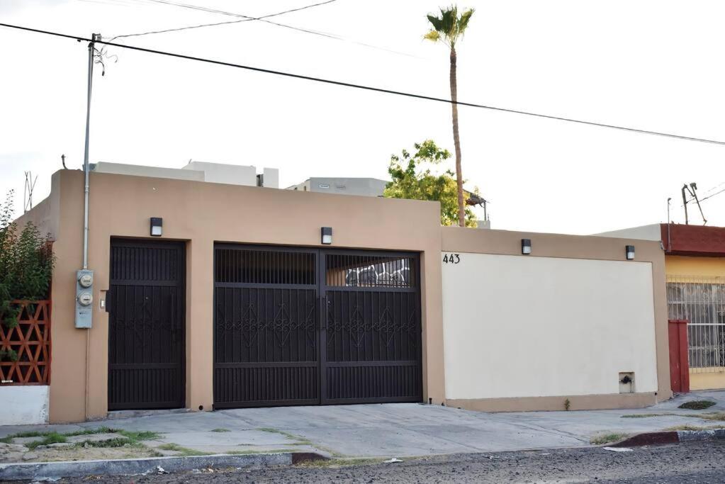 a building with two garage doors and a white billboard at Amplia casa cerca malecón in La Paz