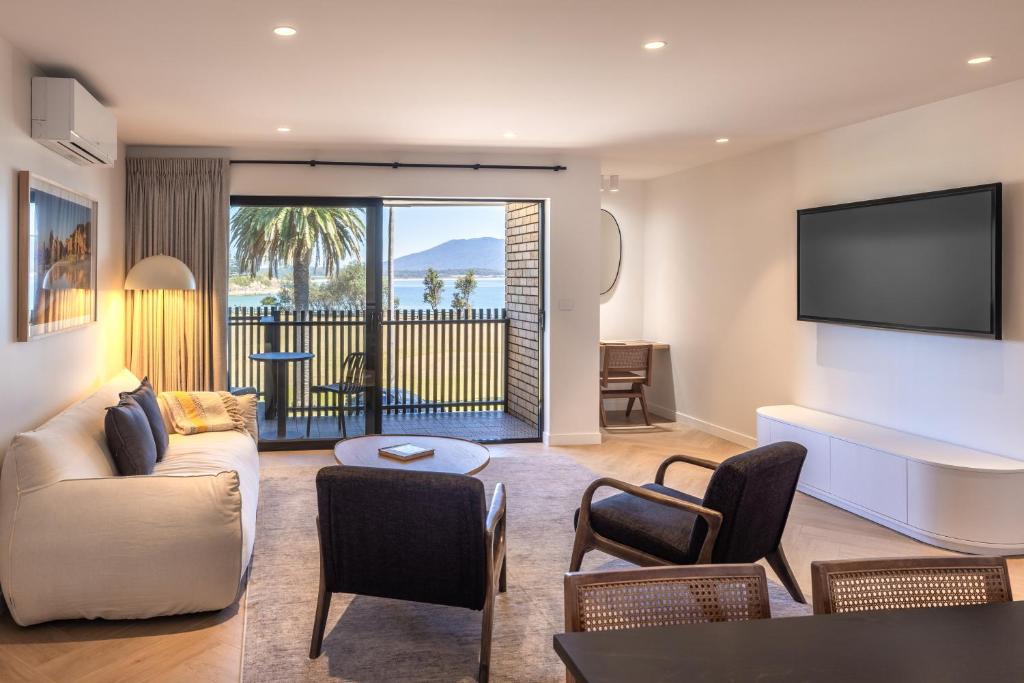 a living room with a couch and a flat screen tv at Bermagui Beach Hotel in Bermagui