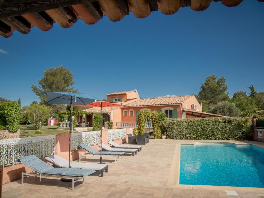 une piscine avec des chaises longues et une maison dans l'établissement Villa Nycou, à Bagnols-en-Forêt