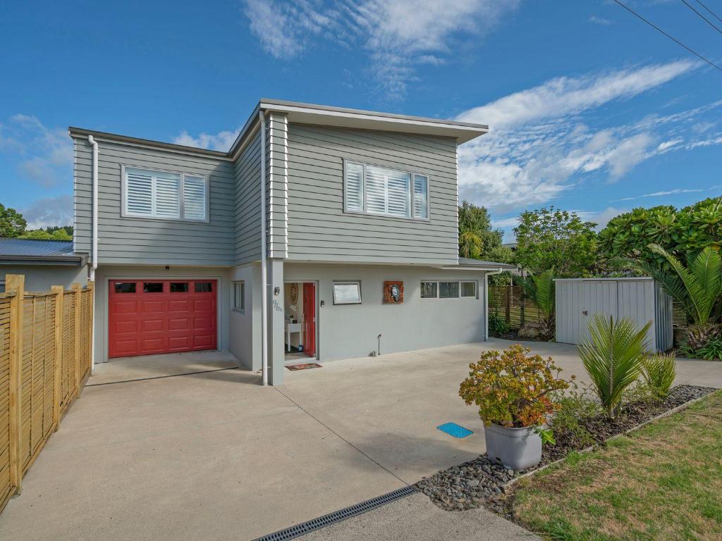 a house with a red garage at Hosts on the Coast Beach on Buffalo in Whitianga
