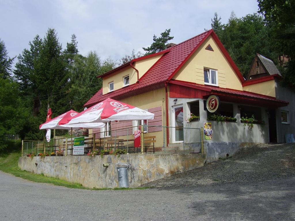 un restaurant avec des parasols en face d'un bâtiment dans l'établissement Rybářská Chata U Sumce, à Stříbro
