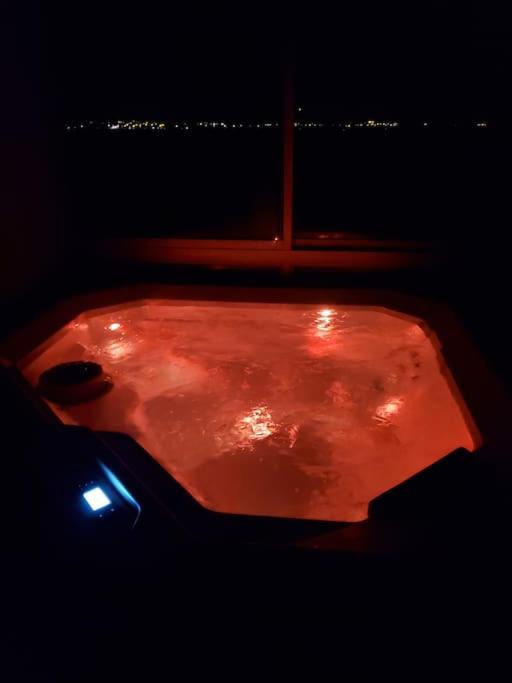 une baignoire rouge avec des lumières dans l'obscurité dans l'établissement Chez Arnaud sauna et jacuzzi, à Saint-Maurice-sur-Loire