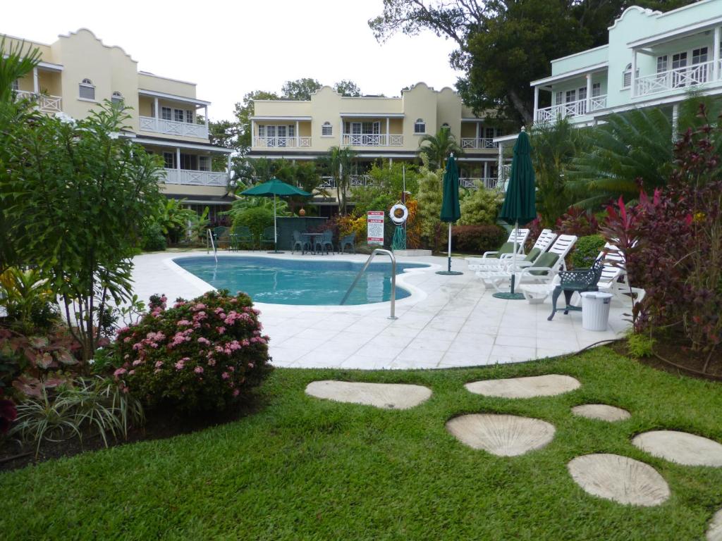 a yard with a swimming pool and some buildings at Margate Gardens in Bridgetown