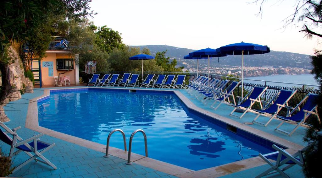 a swimming pool with blue chairs and umbrellas at Baia Serena in Vico Equense