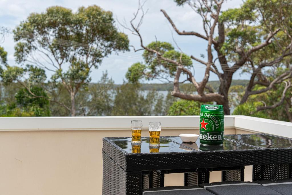 dos vasos de cerveza sentados en una mesa en un balcón en Swan Lake View House, en Berrara