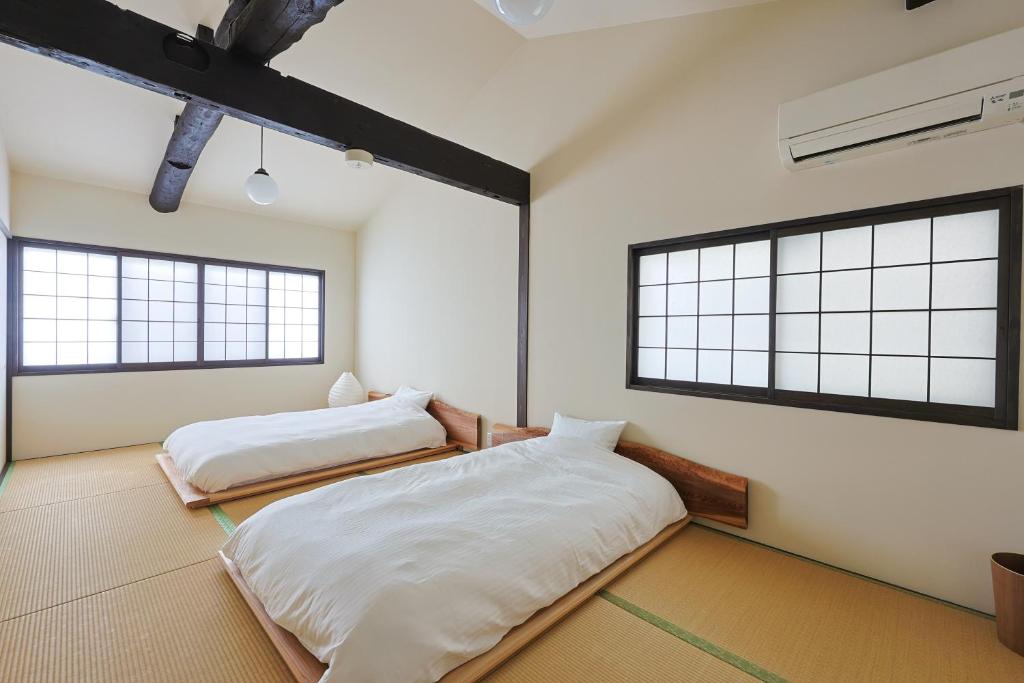 Dos camas en una habitación con dos ventanas. en 二条 椿や, en Kioto