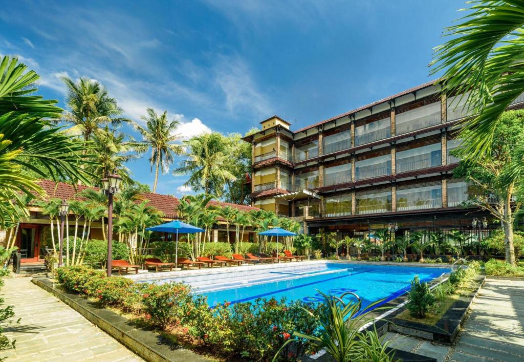 a hotel with a swimming pool and palm trees at Qualia Resort Phu Quoc in Phú Quốc
