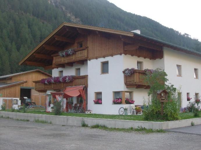 a large white building with a wooden roof at Appartementhaus Honznhof in Längenfeld