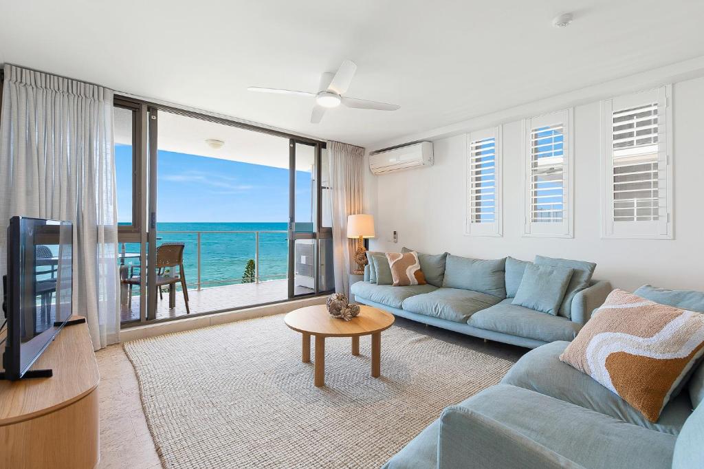 a living room with a blue couch and a view of the ocean at Pacific Beach Resort in Mooloolaba