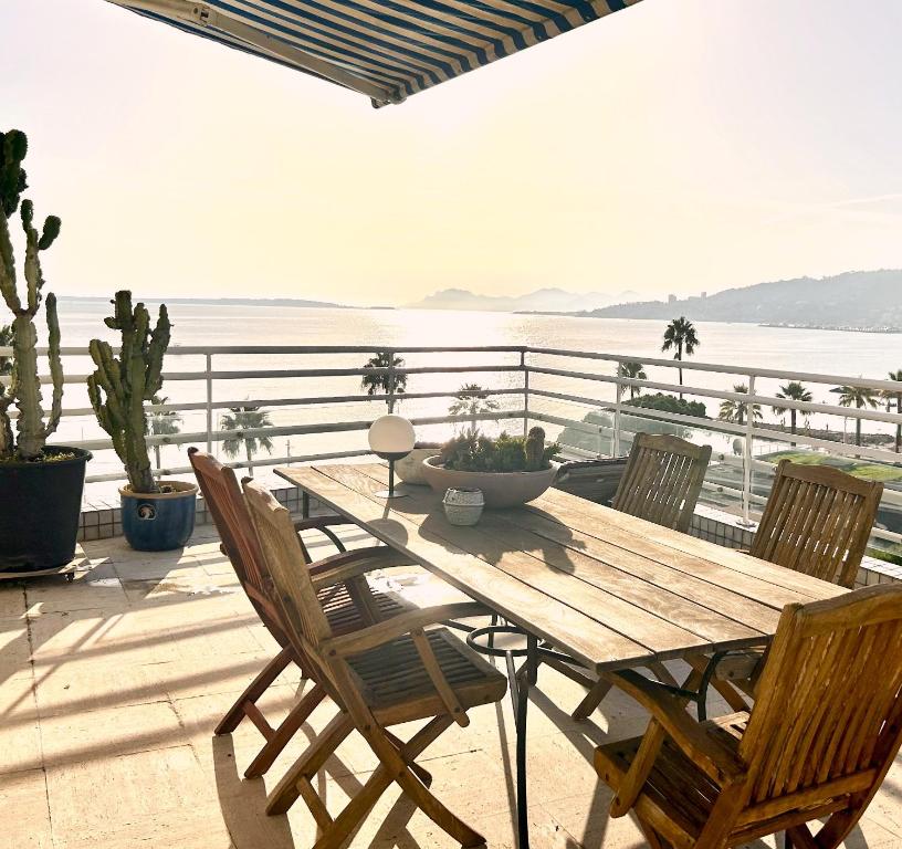 d'une table et de chaises en bois sur un balcon donnant sur l'océan. dans l'établissement Riviera rooftop - front de mer avec terrasse dans le centre, à Antibes
