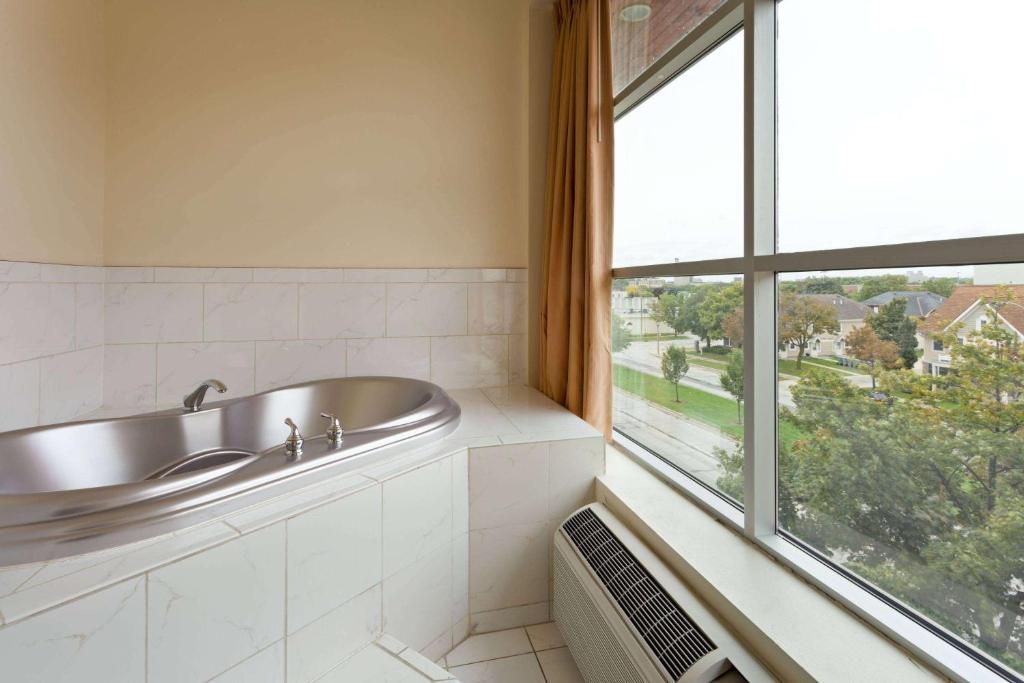 ein Badezimmer mit Waschbecken und großem Fenster in der Unterkunft Days Inn &amp; Suites by Wyndham Milwaukee in Milwaukee