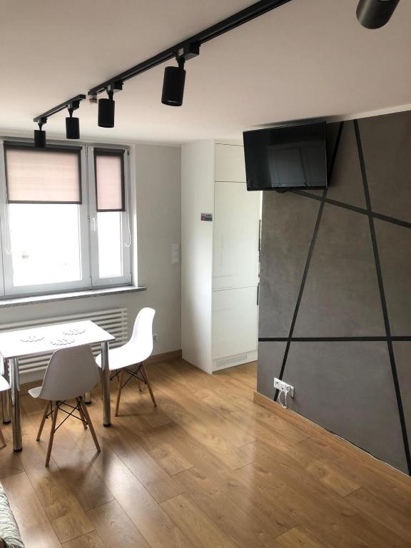 a room with a table and chairs and a kitchen at Apartament Centrum Malbork in Malbork
