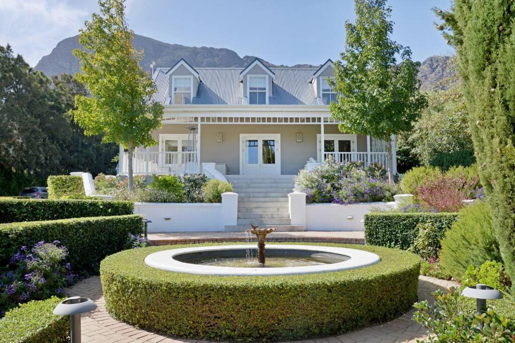 a house with a fountain in the middle of a garden at Farm Lorraine The Loft Cottage in Franschhoek