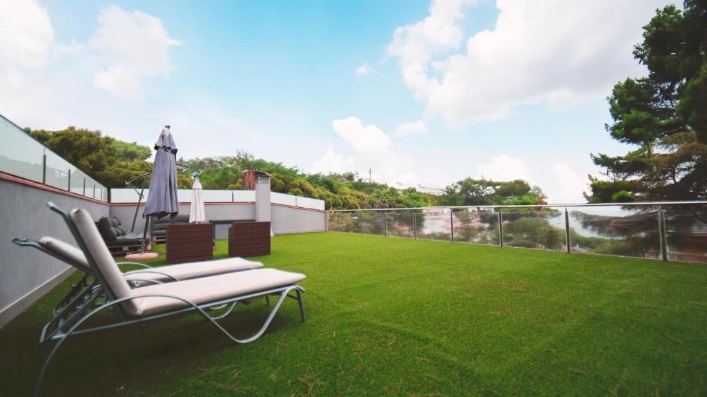 a balcony with a lawn with a chair and an umbrella at SeaHomes Vacations - Villa Serenity Cala Canyelles in Lloret de Mar