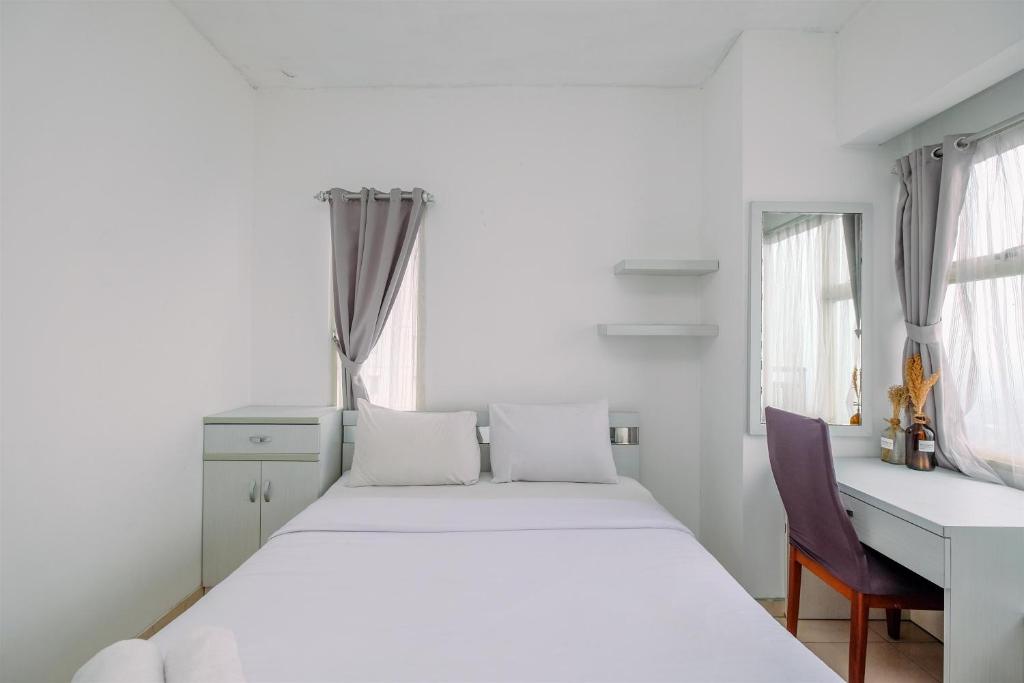 a bedroom with a white bed and a desk and window at Simple and Cozy Living Studio Apartment at Margonda Residence 3 By Travelio in Depok