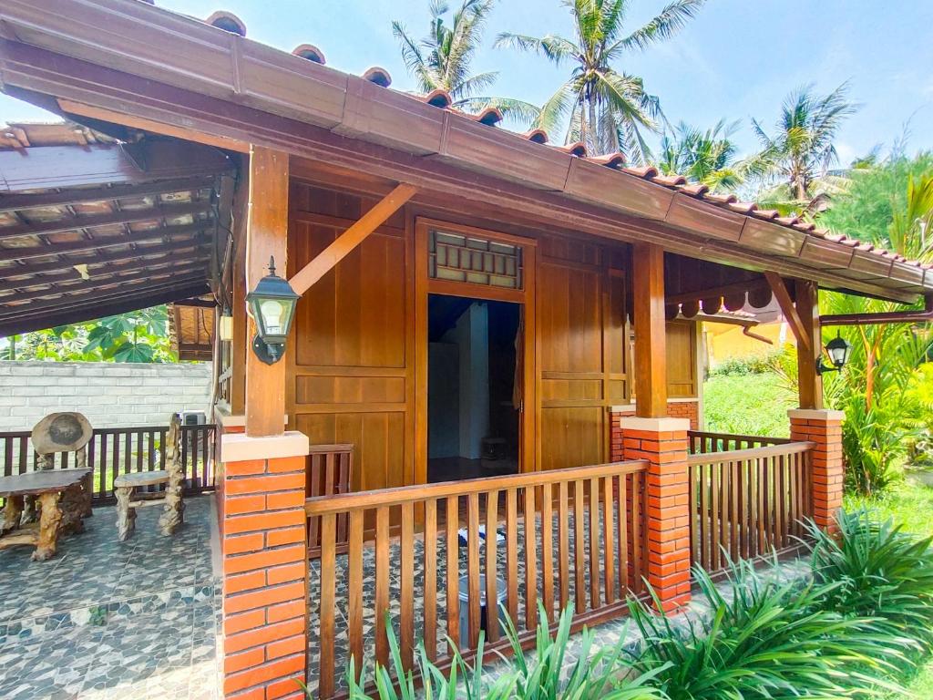 a wooden house with a porch and a bench at RedDoorz near Stasiun Banyuwangi Kota in Glagah