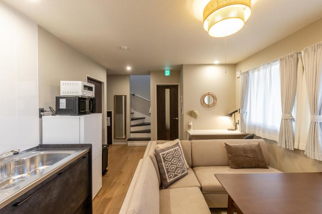 a living room with a couch and a kitchen at Snow House LANKA in Furano