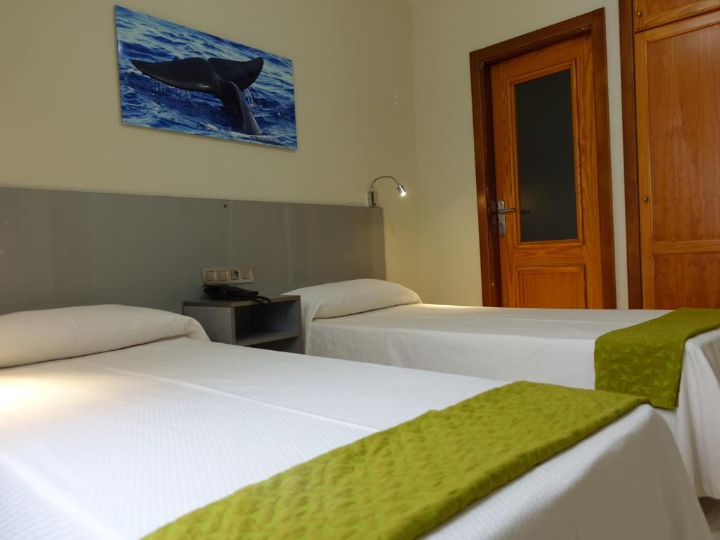 a room with two beds with a whale on the wall at Hotel Andrea´s in Los Cristianos