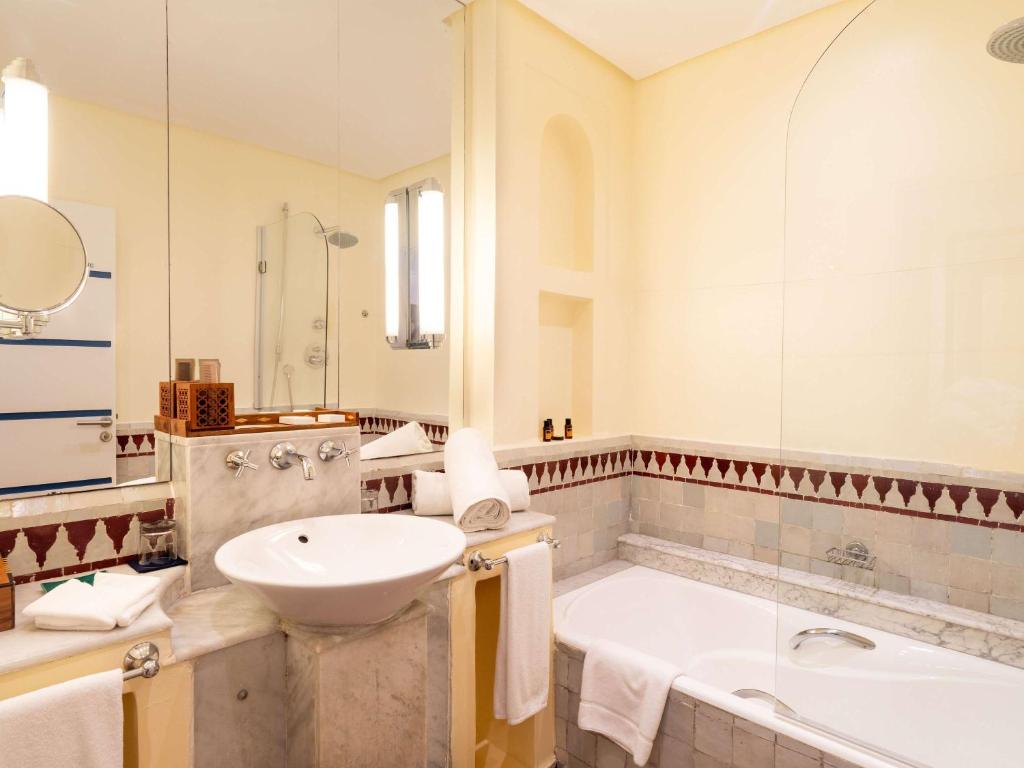 a bathroom with a sink and a bath tub and a sink at Le Médina Essaouira Thalassa Sea & Spa - MGallery Collection in Essaouira
