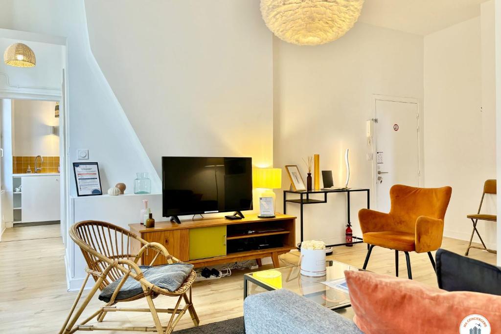 un salon avec une télévision à écran plat et des chaises dans l'établissement L'Oasis Havrais - Centre Historique, au Havre