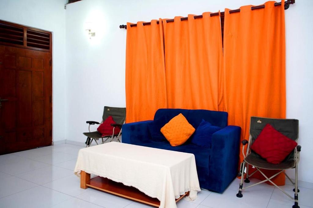 卡卢特勒DRS Luxury Holiday Home的房间里有一把蓝色椅子和一扇橙色窗帘。