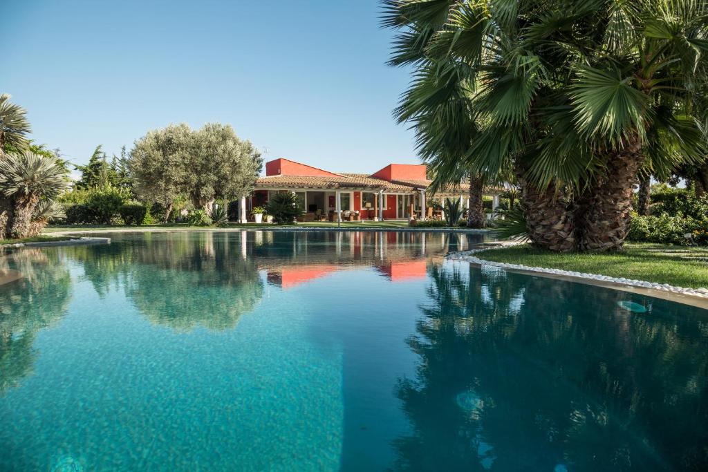 een zwembad voor een huis met palmbomen bij Il Giardino degli Dei in San Leone