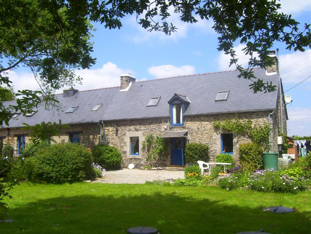 una vieja casa de piedra con césped delante en Le Boterff Gites et Camping en Saint-Mayeux