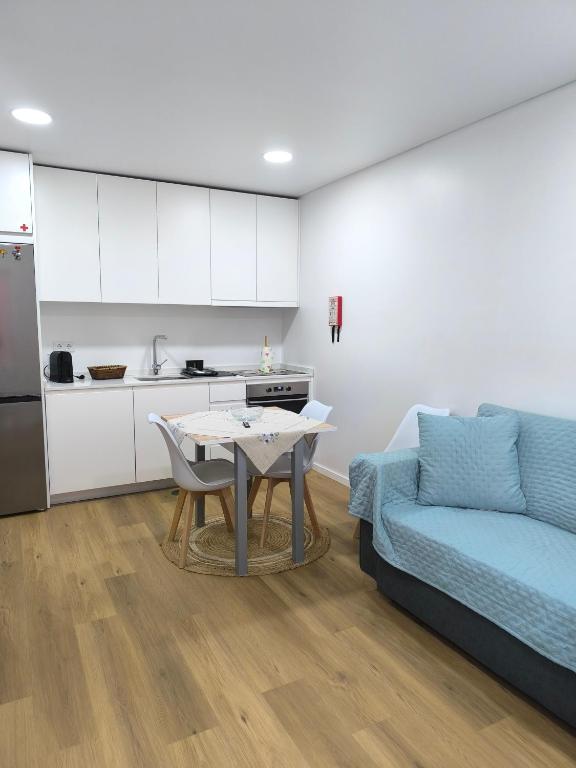 a kitchen and a living room with a table and a couch at Alojamento Emílio T1 in Gafanha da Encarnação