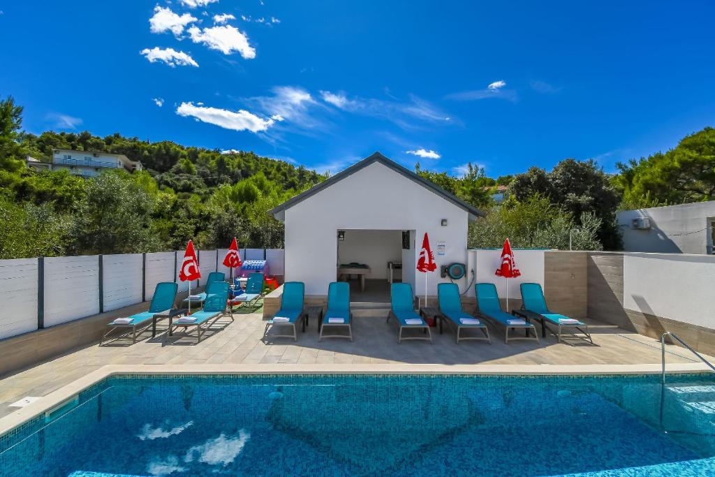 a pool with chairs and umbrellas next to a building at Apartments Villa Niko in Trogir