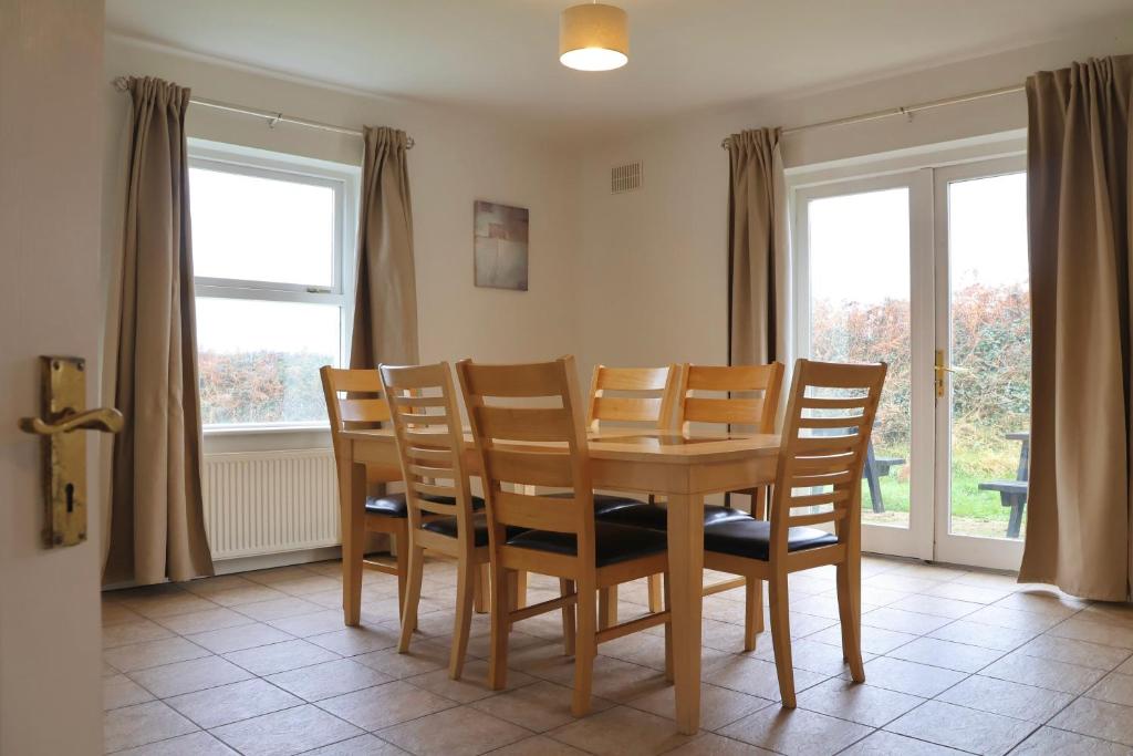 a dining room with a table and chairs and windows at Doolin Village Lodges in Doolin