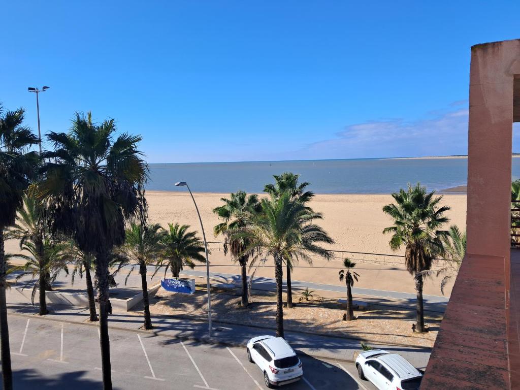 a parking lot with palm trees and a beach at PLAYA PASEO MARITIMo in Sanlúcar de Barrameda
