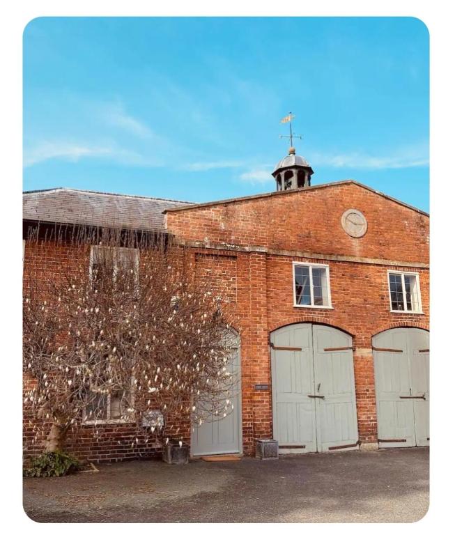 a red brick building with two garage doors and a tower at The Coach House in Berriew