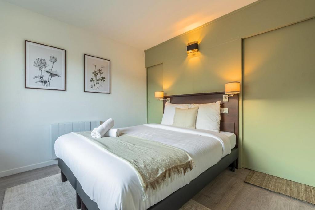 - une chambre avec un grand lit et deux photos sur le mur dans l'établissement Studio proche Université Catholique & centre-ville, à Lille