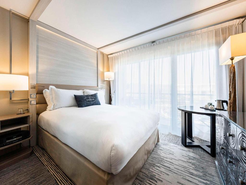 a hotel room with a large bed and a window at Sofitel Quiberon Thalassa sea & spa in Quiberon