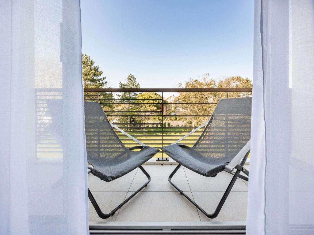 two chairs sitting on a balcony looking out a window at Sofitel Quiberon Thalassa sea & spa in Quiberon