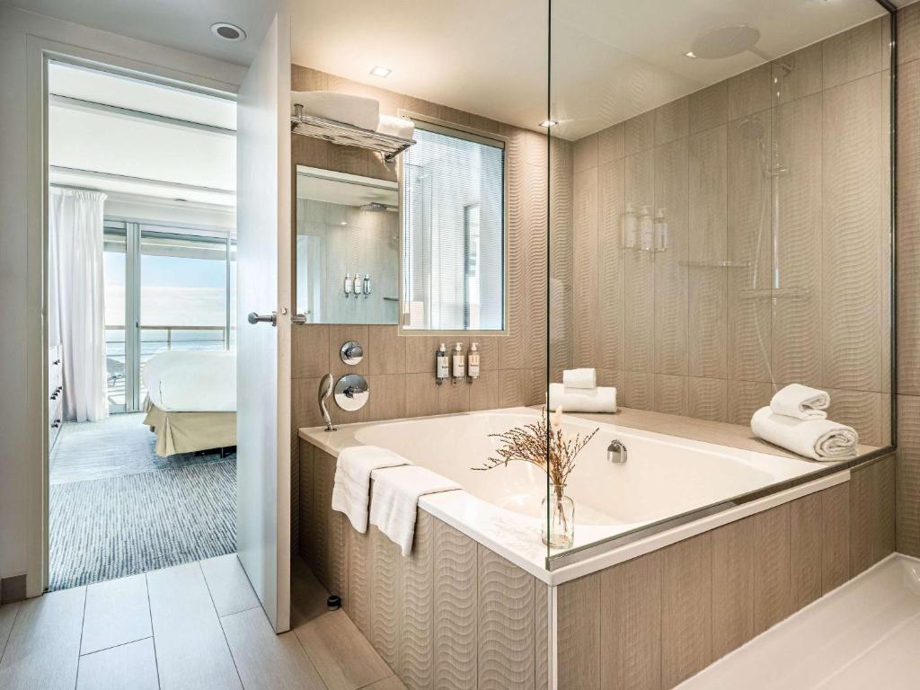 a bathroom with a large tub and a bedroom at Sofitel Quiberon Thalassa sea & spa in Quiberon