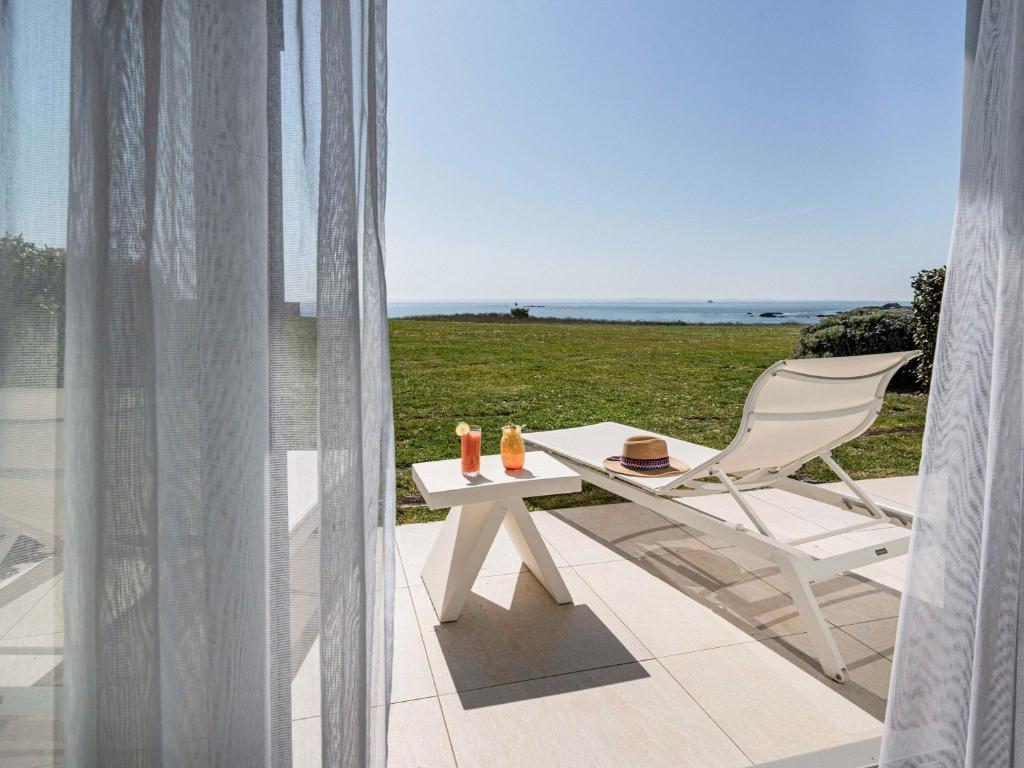 a white chair sitting on a patio with a table at Sofitel Quiberon Thalassa sea & spa in Quiberon