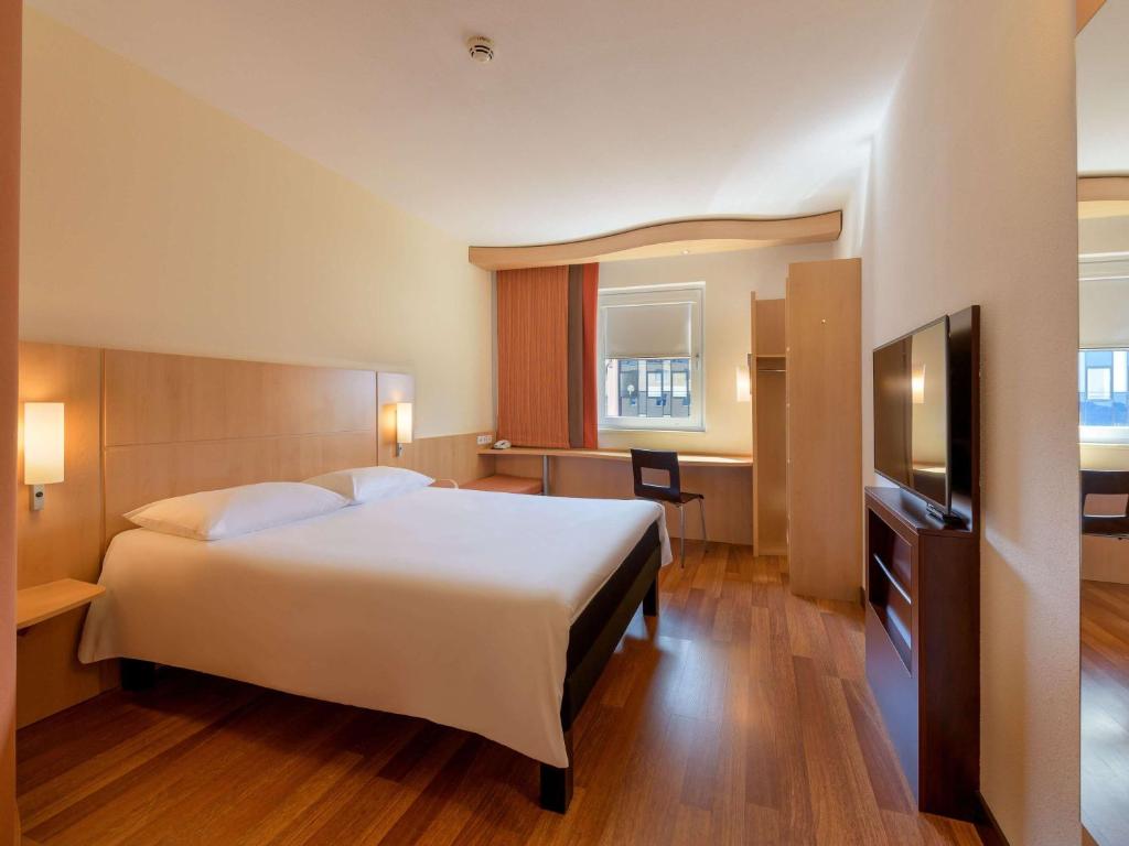 a bedroom with a large white bed and a desk at ibis Stuttgart Airport Messe in Leinfelden-Echterdingen