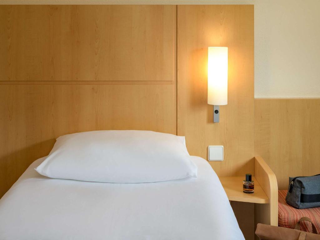 a bedroom with a white bed and a lamp at ibis Stuttgart Airport Messe in Leinfelden-Echterdingen
